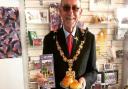 Saffron Walden mayor Richard Porch in Saffron Walden Tourist Information Centre, supporting English Tourism Week 2022, with a tourism leaflet and a plate of saffron buns