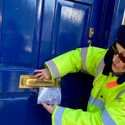 Trilby Roberts posts a flyer through Kemi Badenoch MP's office door in Saffron Walden