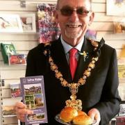 Saffron Walden mayor Richard Porch in Saffron Walden Tourist Information Centre, supporting English Tourism Week 2022, with a tourism leaflet and a plate of saffron buns